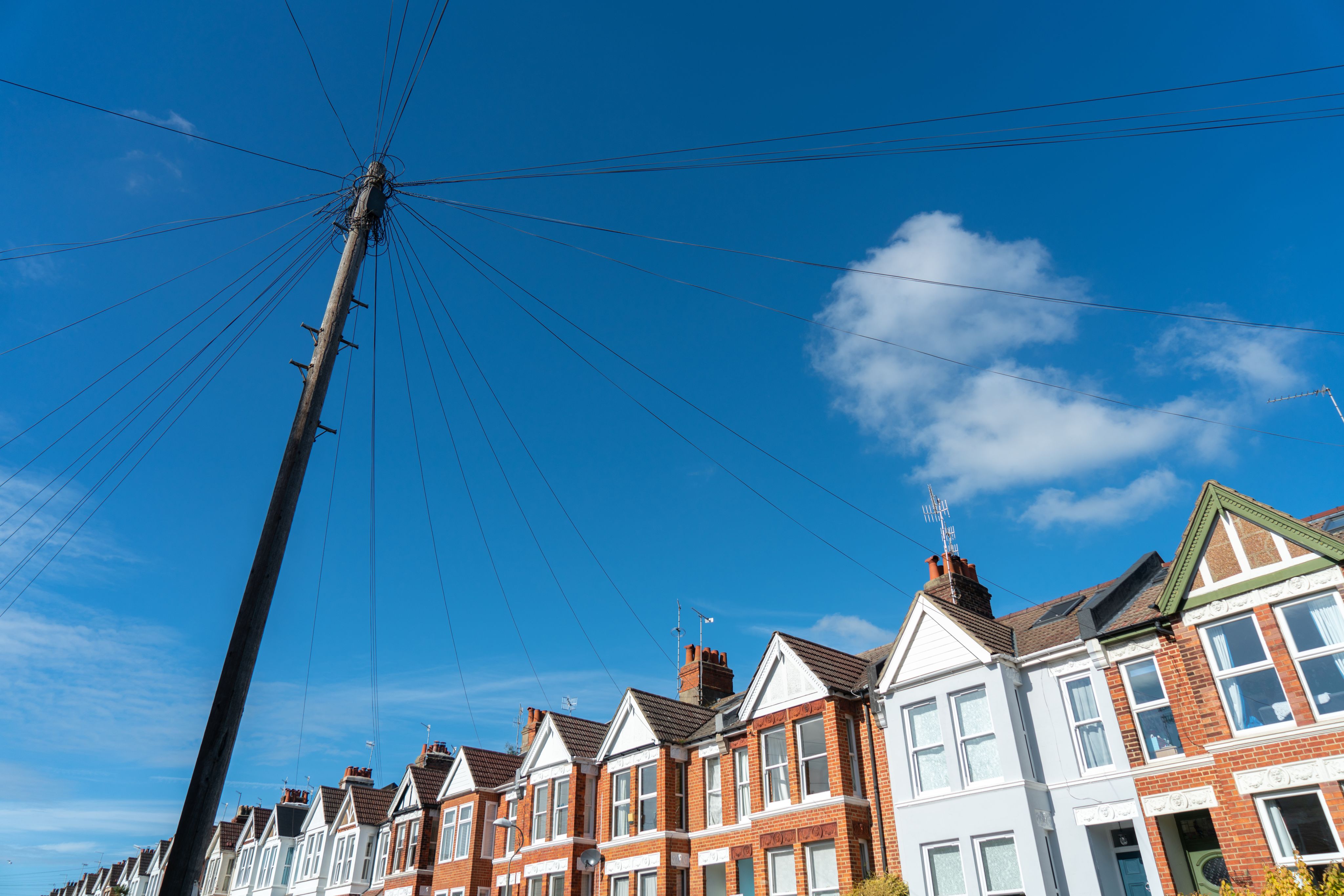 Old vintage wood telephone poles cable construction style in townhouse area in UK. Credit: Adobe Stock / wittayayut