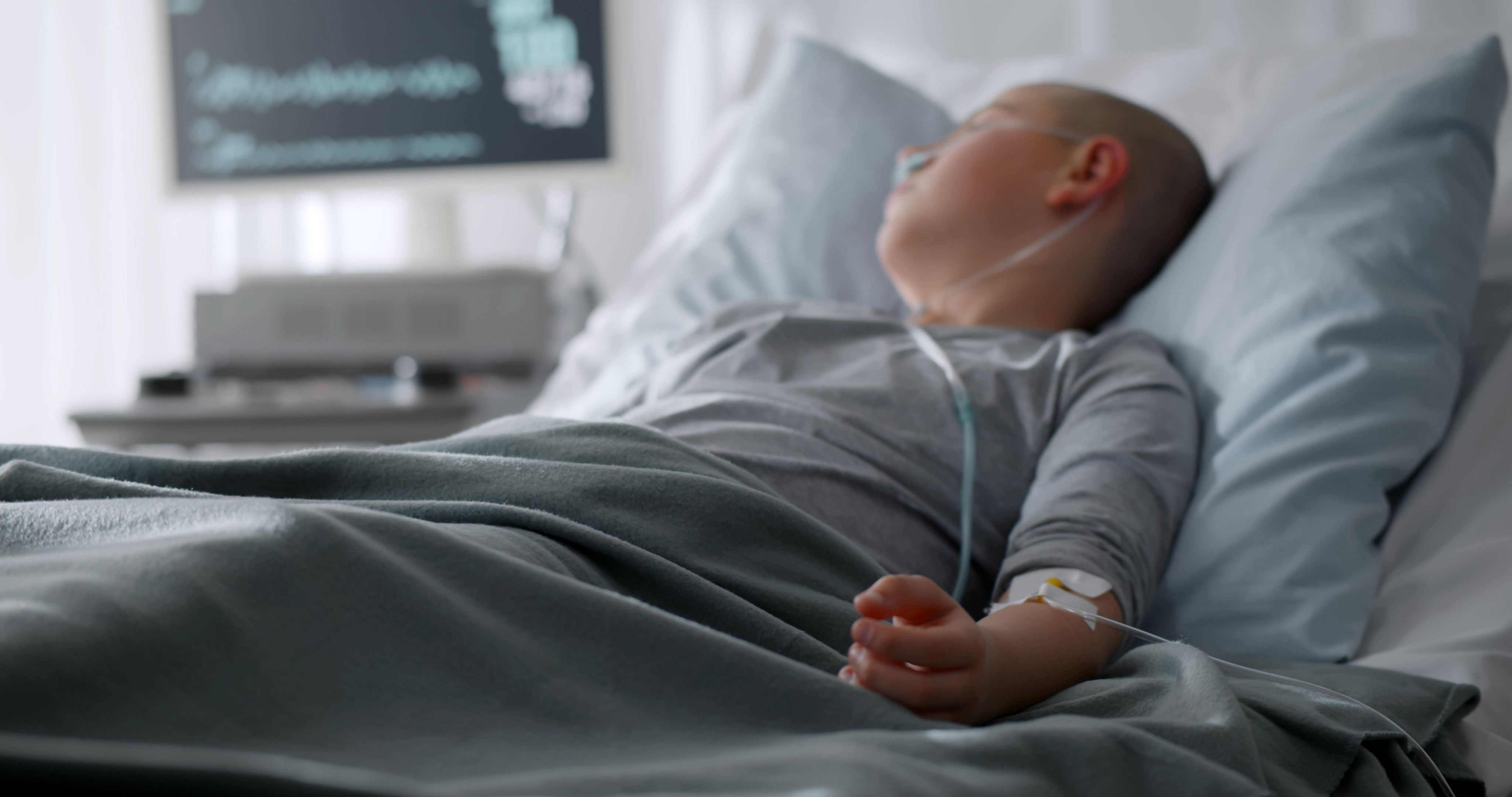 A chemotherapy patient lying in a hospital bed with a tube attached to their arm