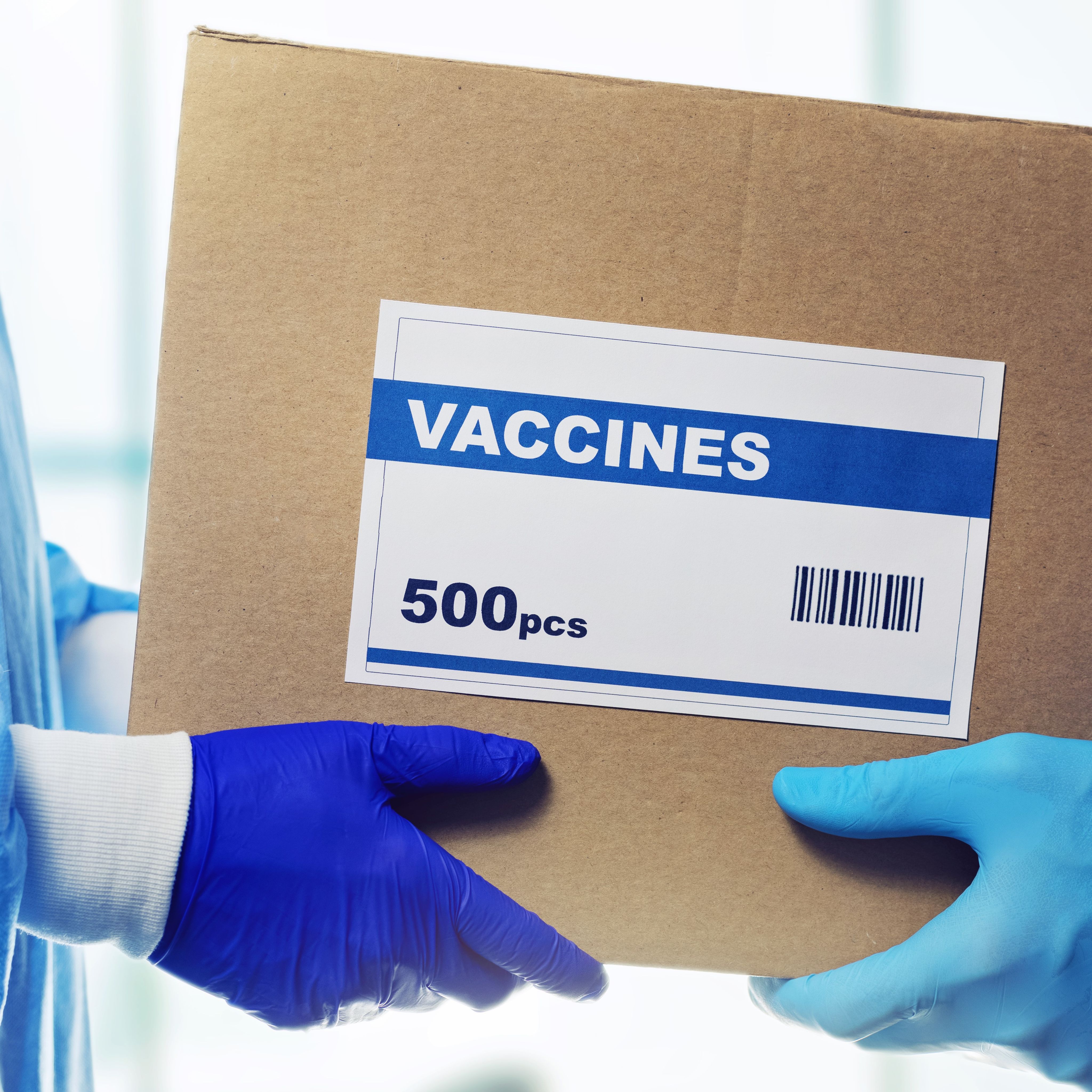 A photograph of a box of vaccines being handed over from one person to another