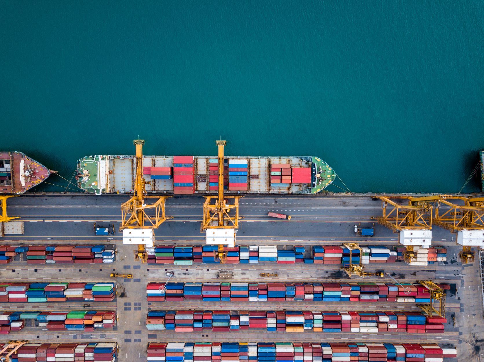 An aerial photograph of a docked container ship being loaded