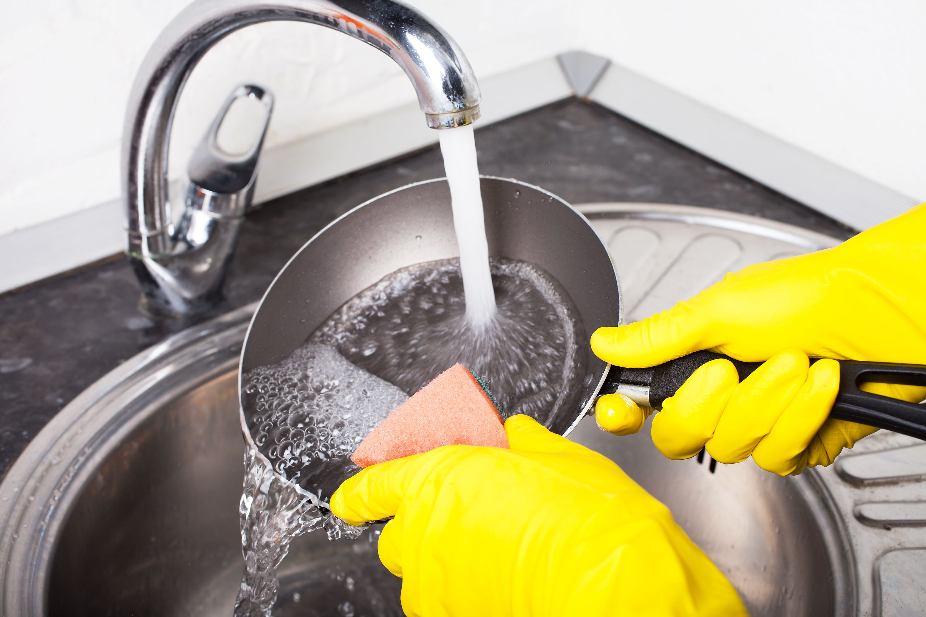 Washing a non-stick frying pan under running water