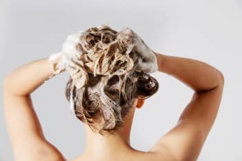 Woman shampooing her hair, viewed from the back