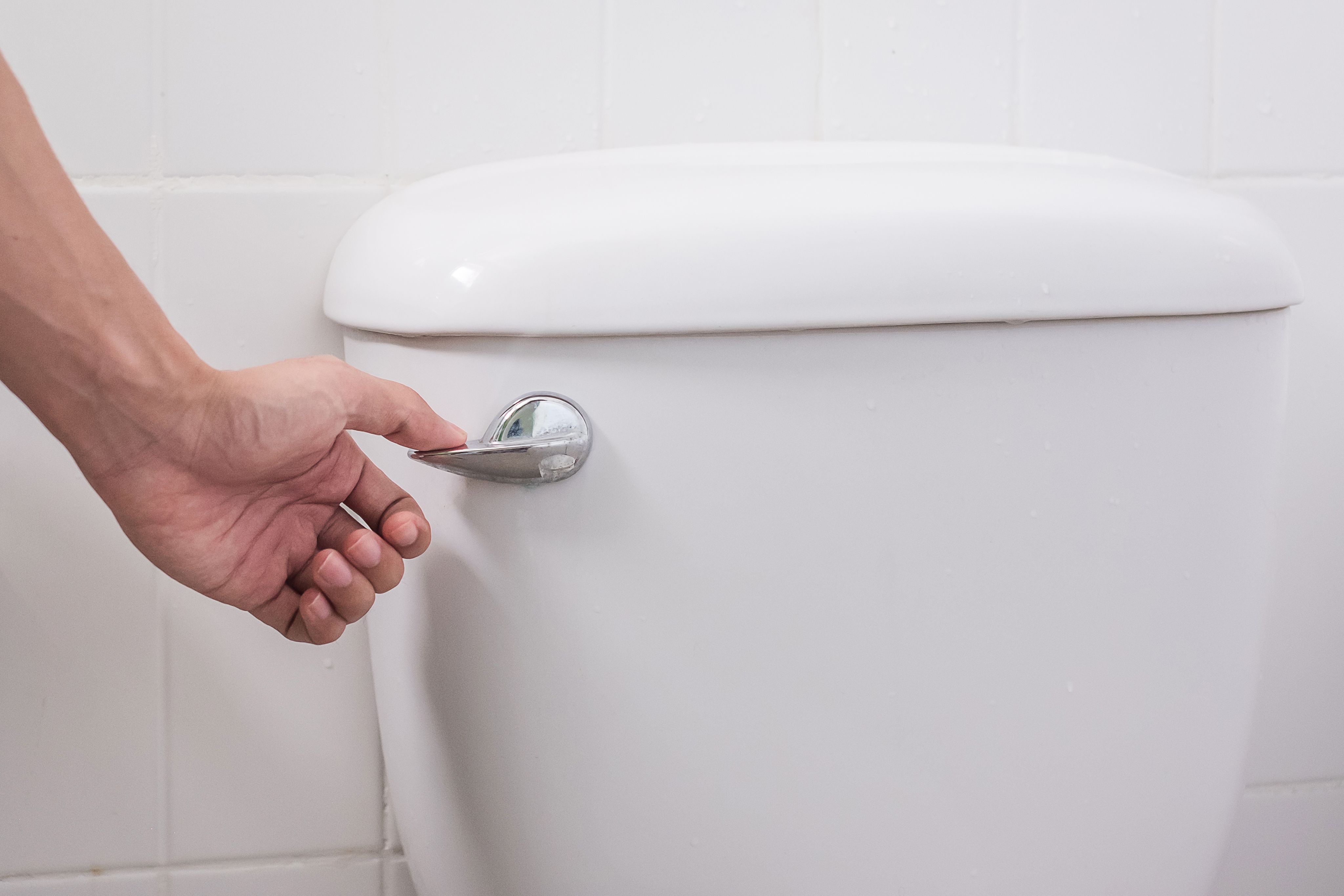 Close up of hand flushing a toilet