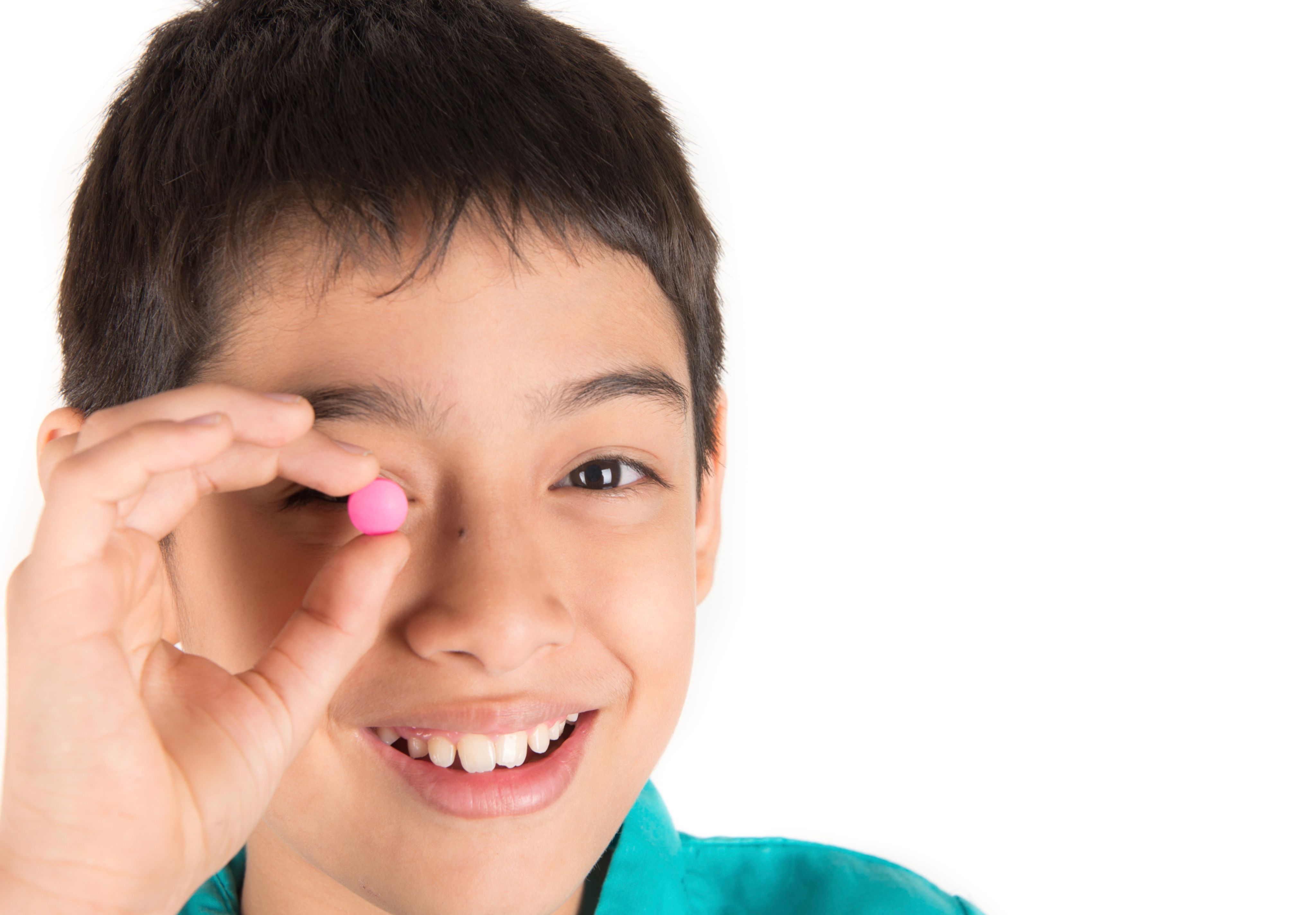 Boy holding a pink pill to his eye